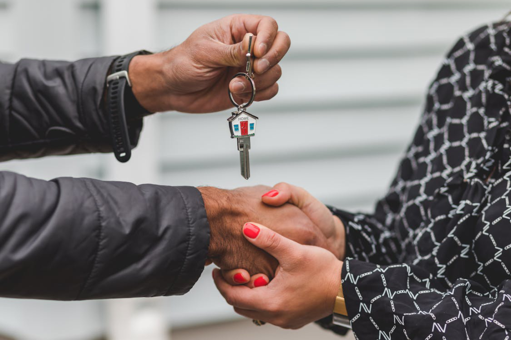 Two people are exchanging home keys and shaking hands